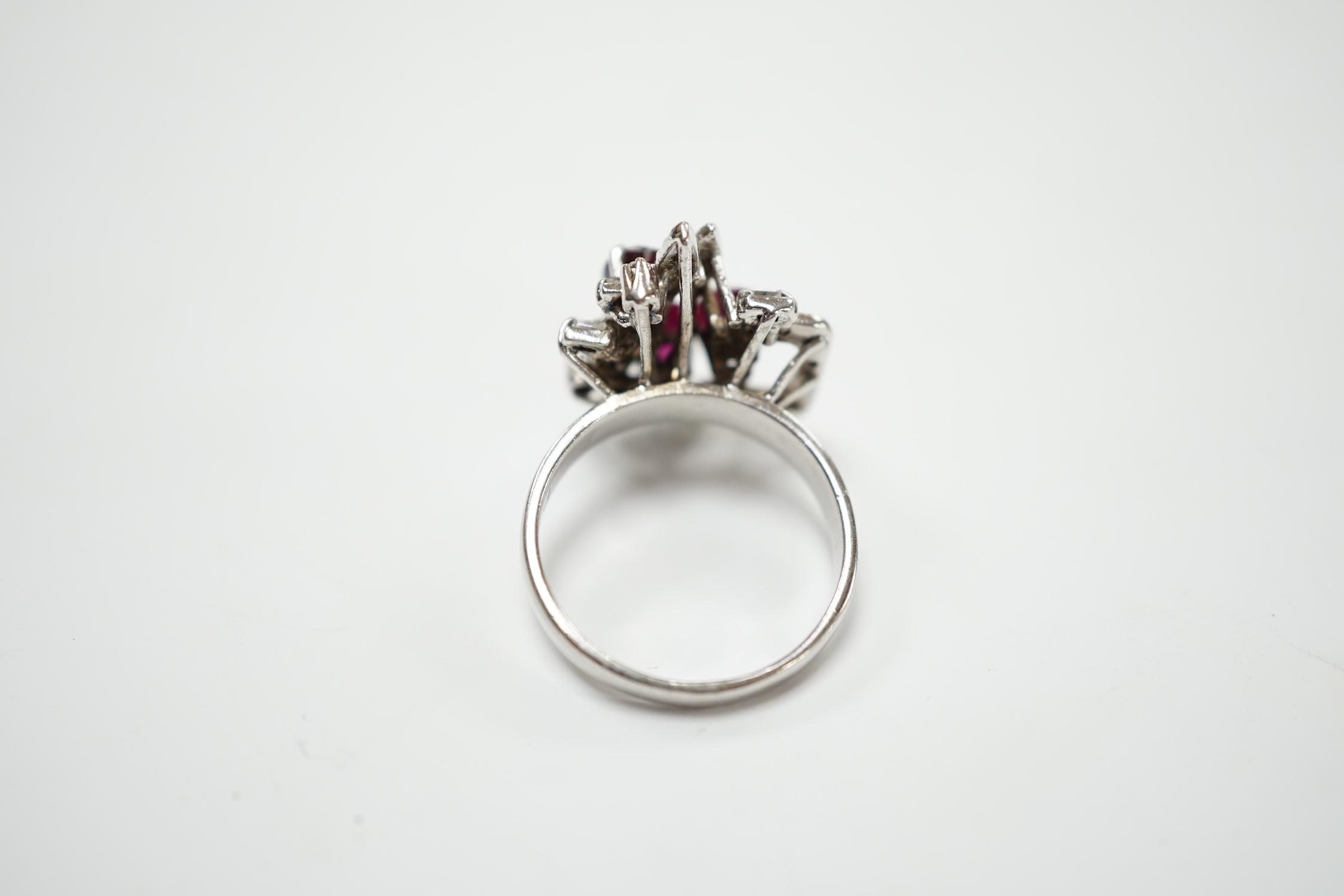 A recent 18k white metal, ruby and diamond cluster set modernist dress ring, size N/O, gross weight 5.7 grams.